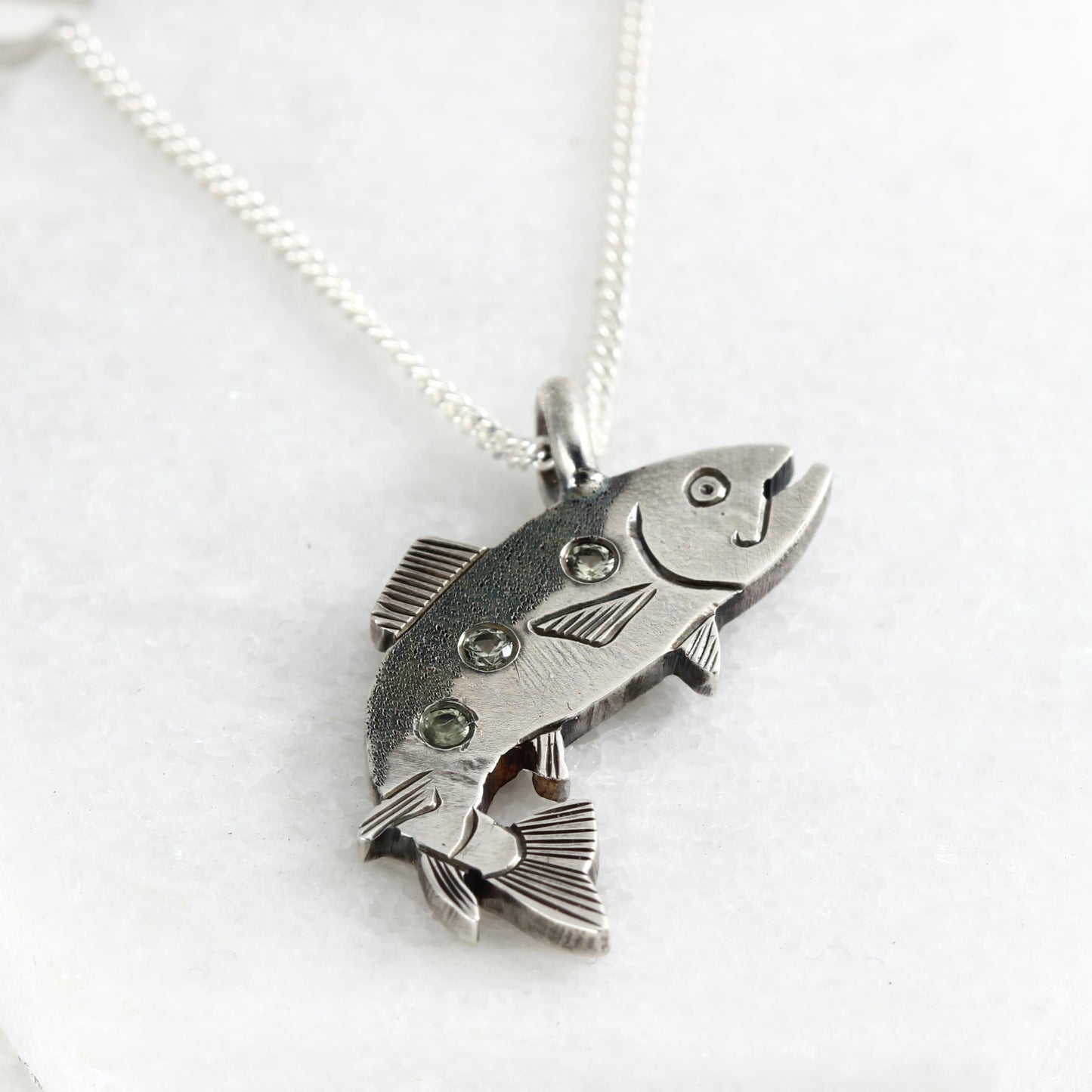 Sterling silver hand-fabricated jumping trout pendant with three shimmering Montana sapphires.