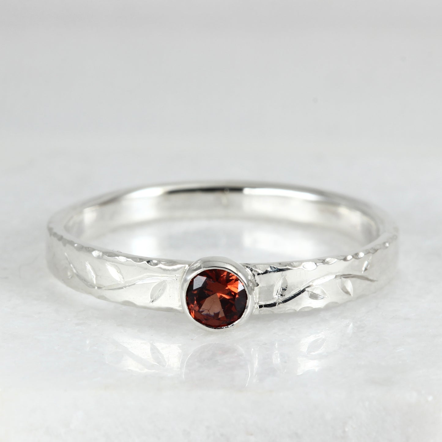 Front view of the Tendril Solitaire Ring in sterling silver, showing the gemstone and the hand engraved vine.