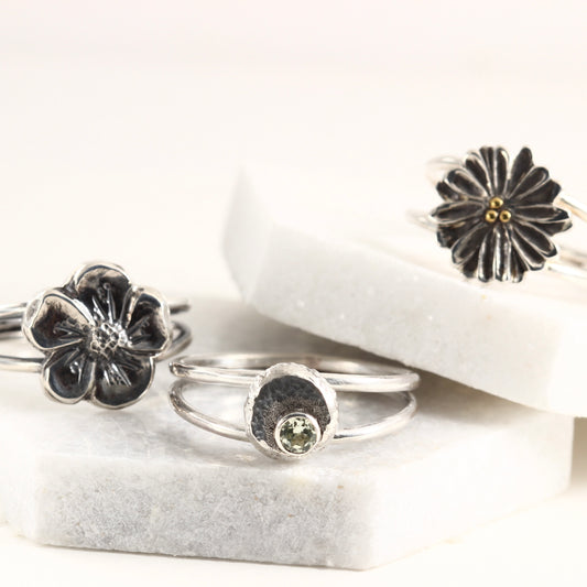 A group of rings from the Wild Blooms collection, sterling silver and hand formed shown on white marble tile