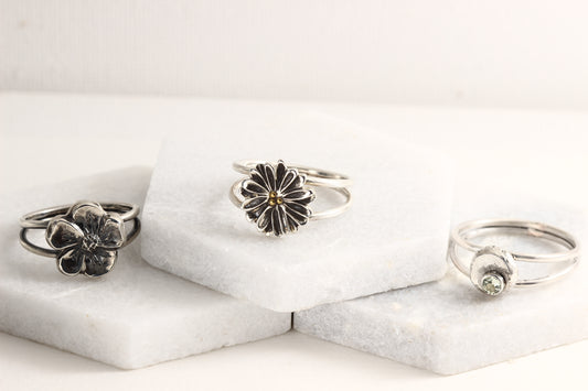 Several rings from the Wild Blooms collection in sterling silver, handcrafted flower rings, on a white marble background