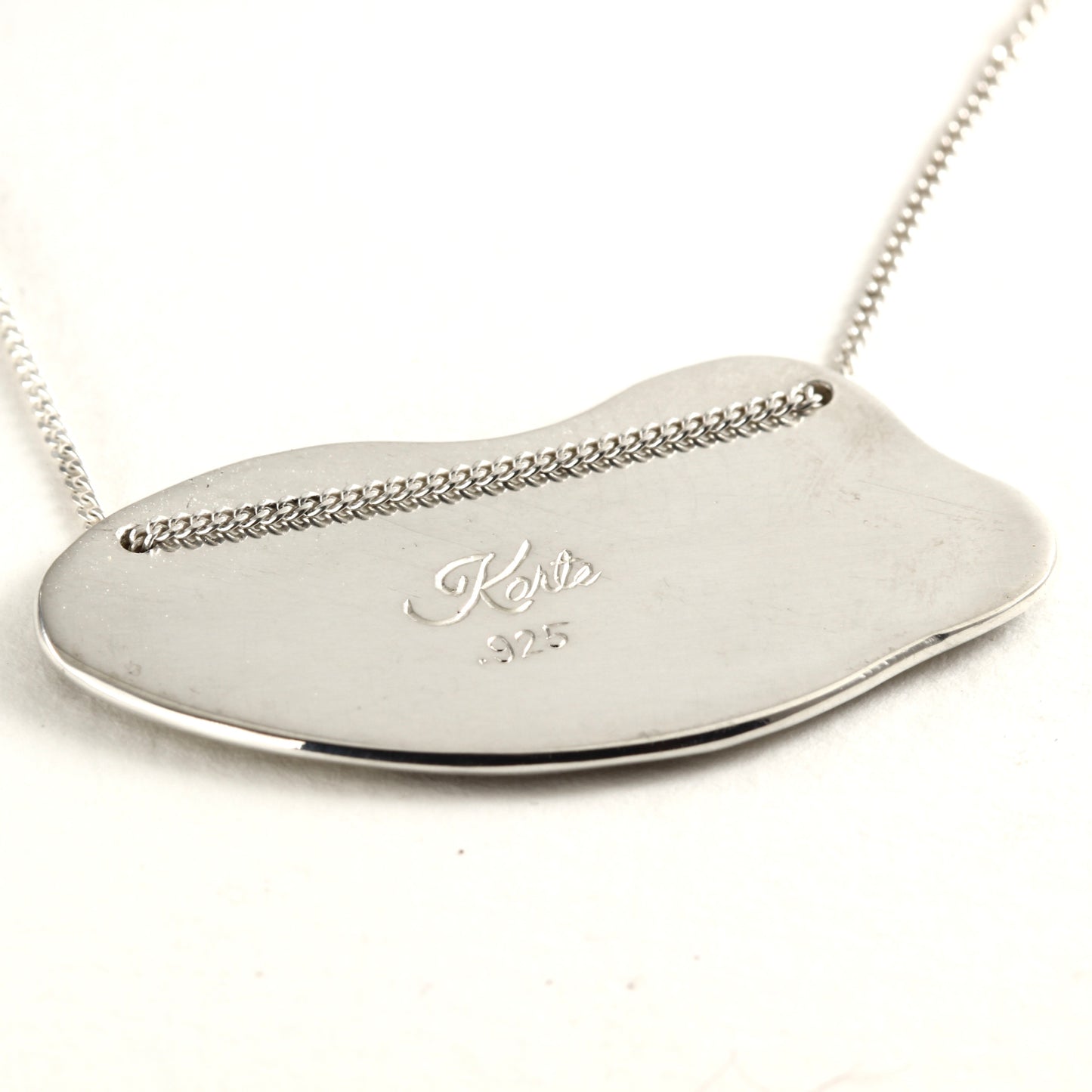 Back Side of Wild Meadow Spring Branch Pendant in sterling silver with gold accents, a hand carved flower pendant shown on white marble tile
