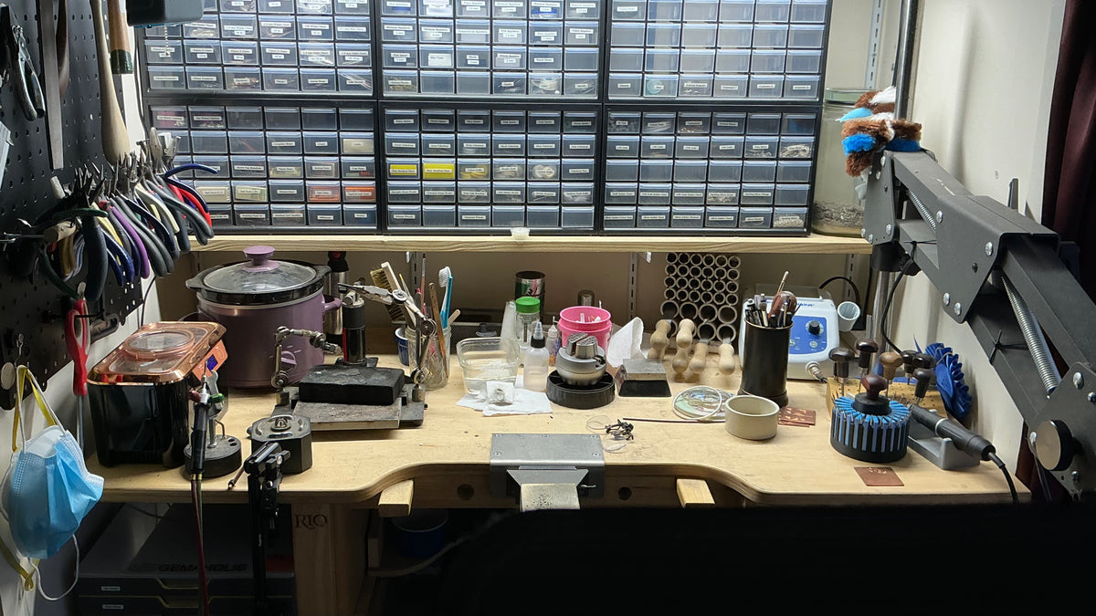 Shows a working jewelers bench with tools on the left, lots of drawers, and a microscope on the right.