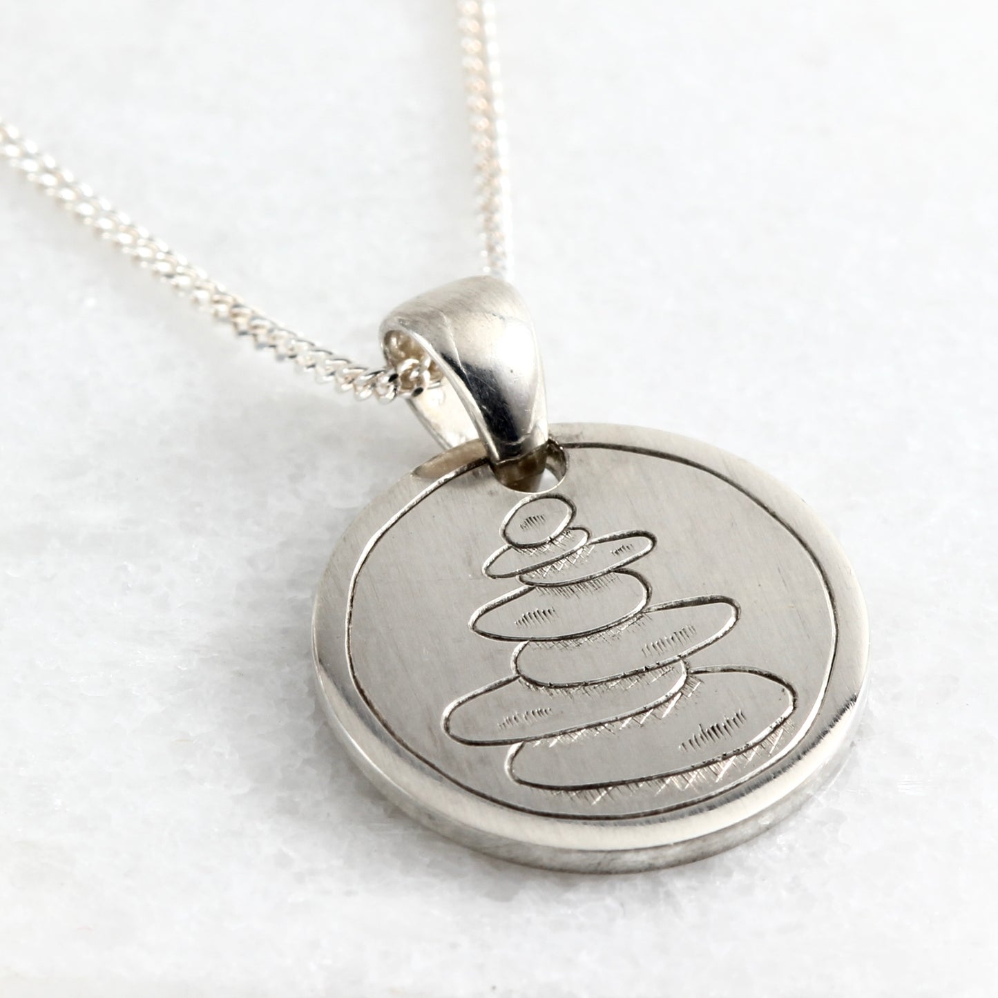 Small hand-engraved sterling silver pendant featuring a cairn