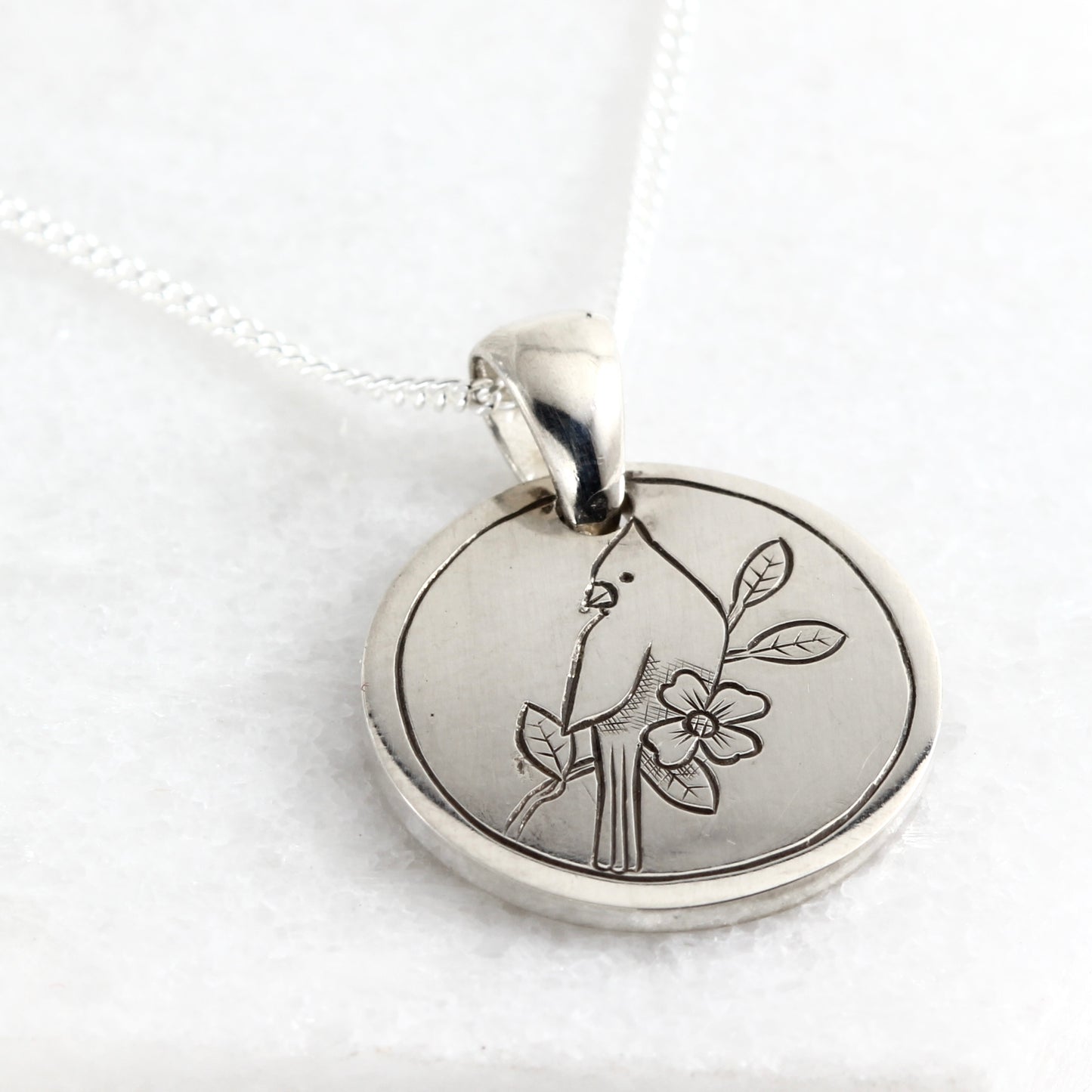 Small hand-engraved sterling silver pendant featuring a cardinal and dogwood bloom