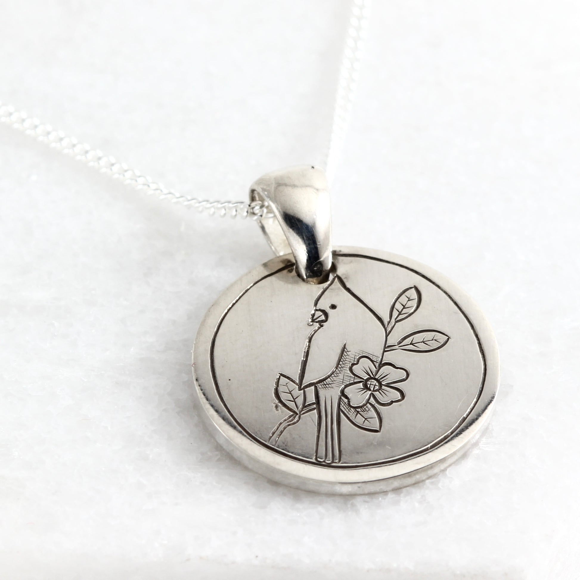 Small hand-engraved sterling silver pendant featuring a cardinal and dogwood bloom