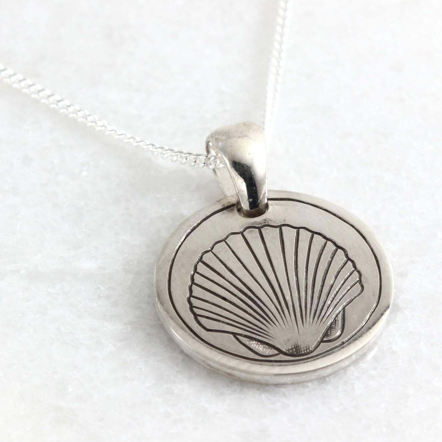 Small hand-engraved sterling silver pendant featuring a clam shell