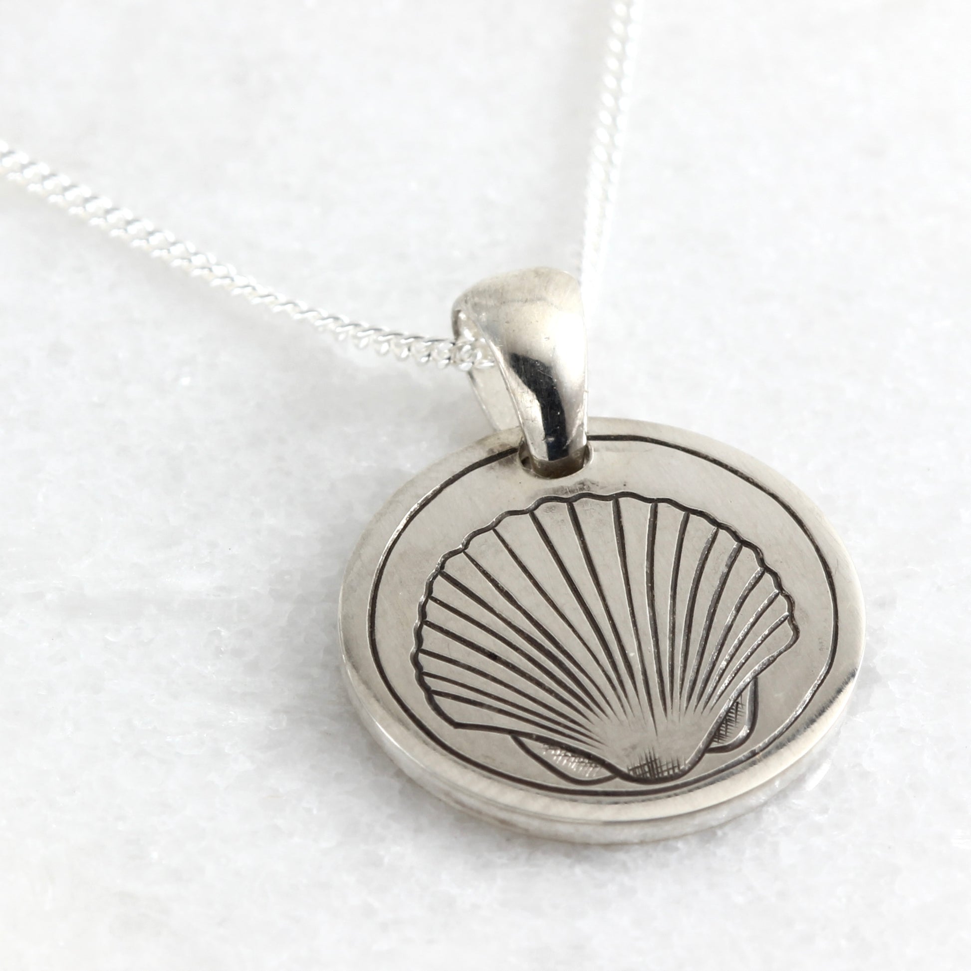 Small hand-engraved sterling silver pendant featuring a clam shell
