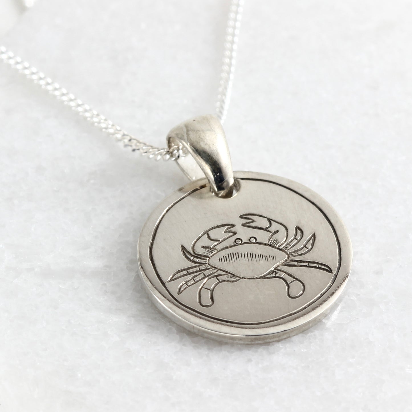 Small hand-engraved sterling silver pendant featuring a crab