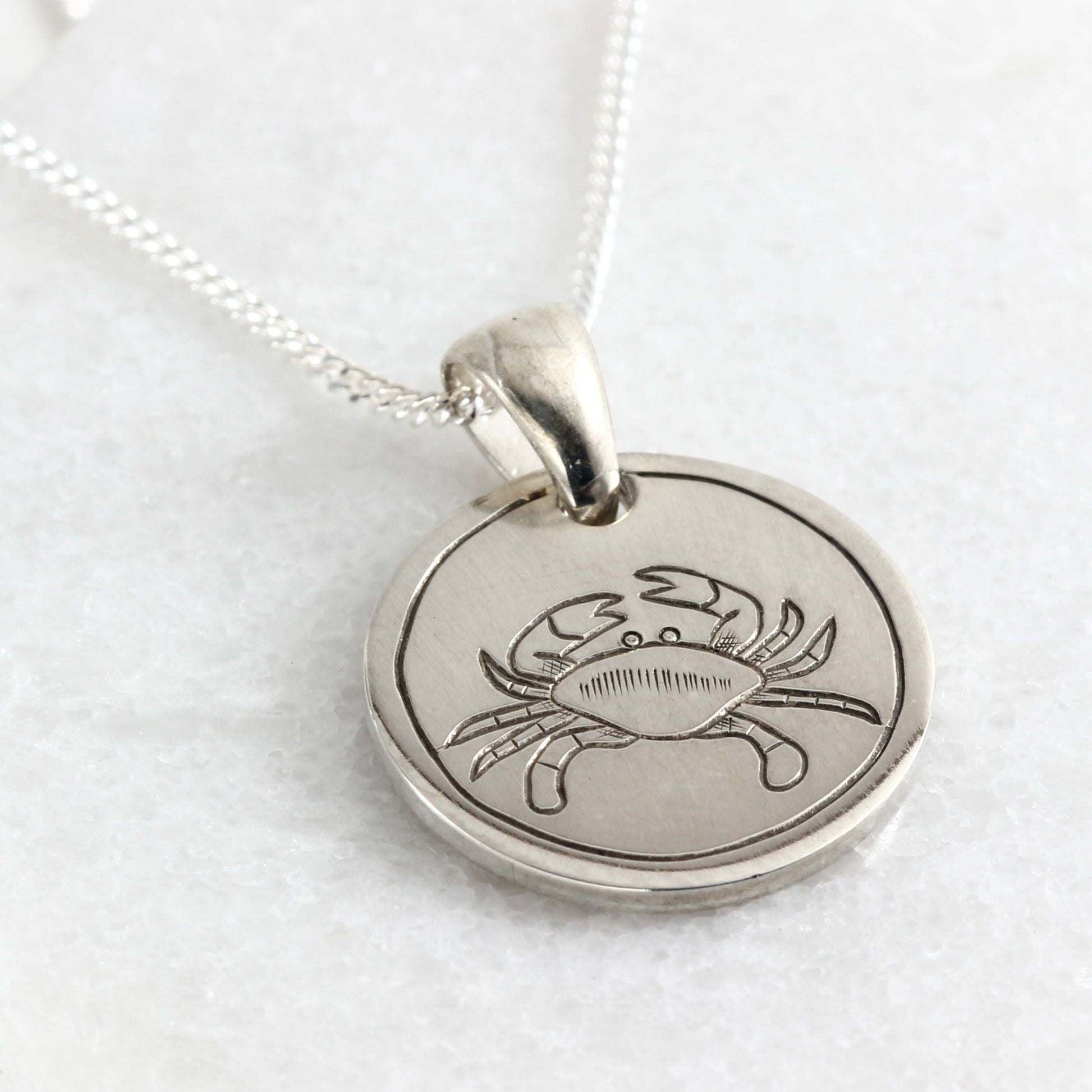 Small hand-engraved sterling silver pendant featuring a crab