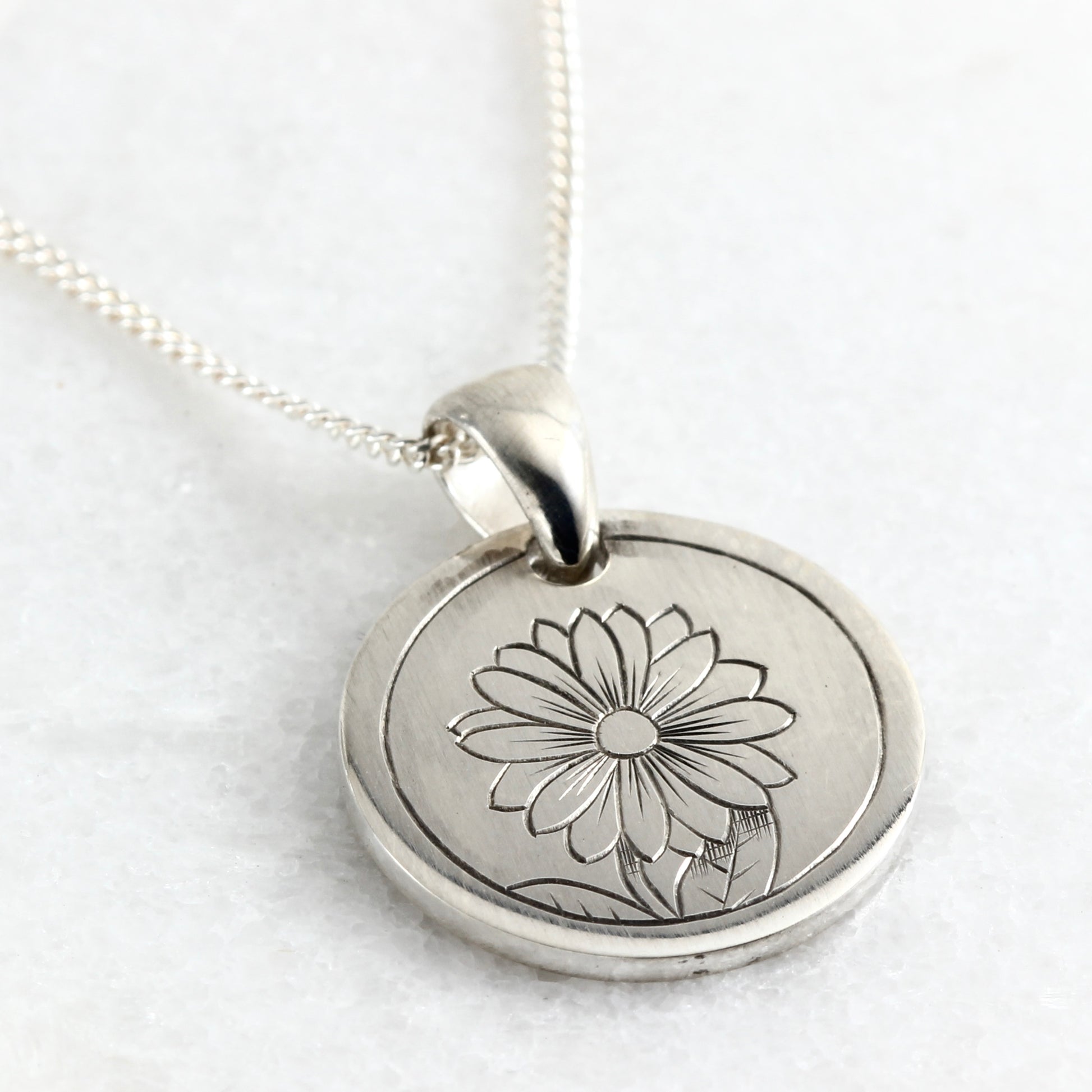 Small hand-engraved sterling silver pendant featuring a daisy