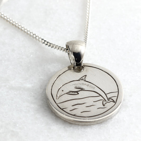 Small hand-engraved sterling silver pendant featuring a dolphin