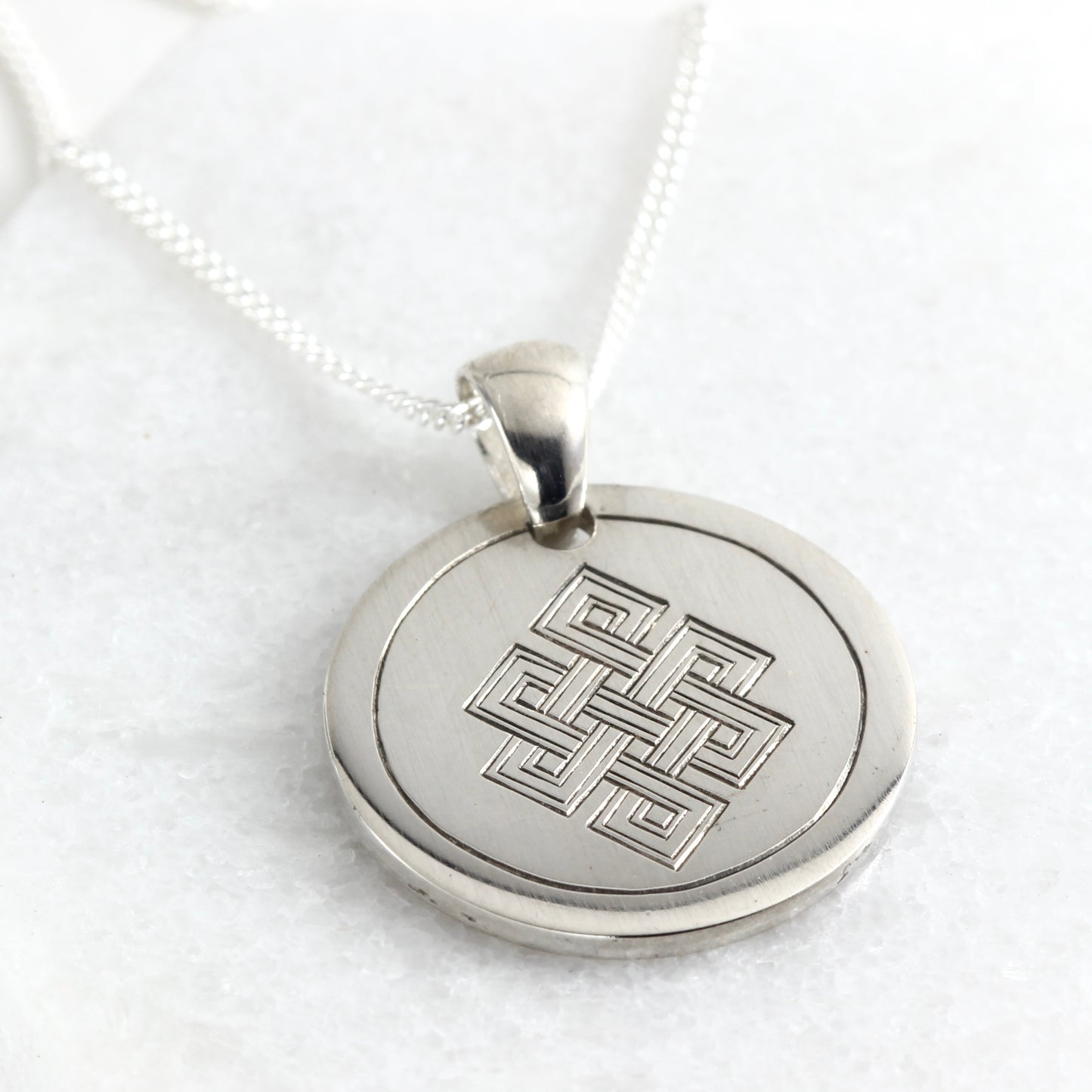 Small hand-engraved sterling silver pendant featuring an endless knot