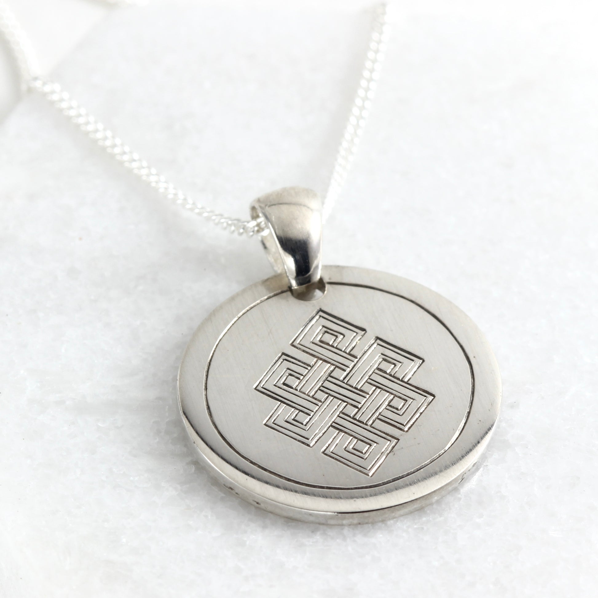 Small hand-engraved sterling silver pendant featuring an endless knot