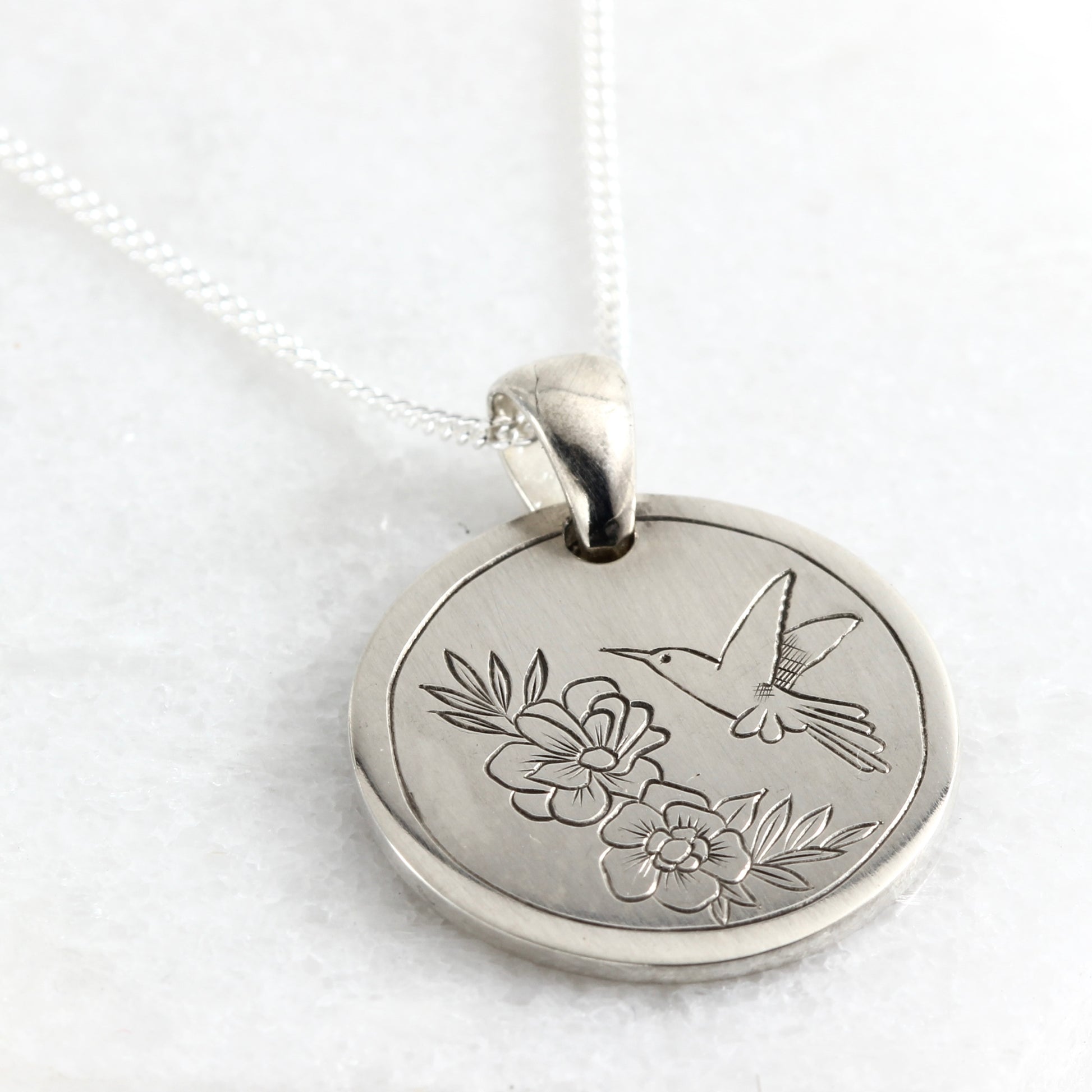 Small hand-engraved sterling silver pendant featuring a hummingbird and flower