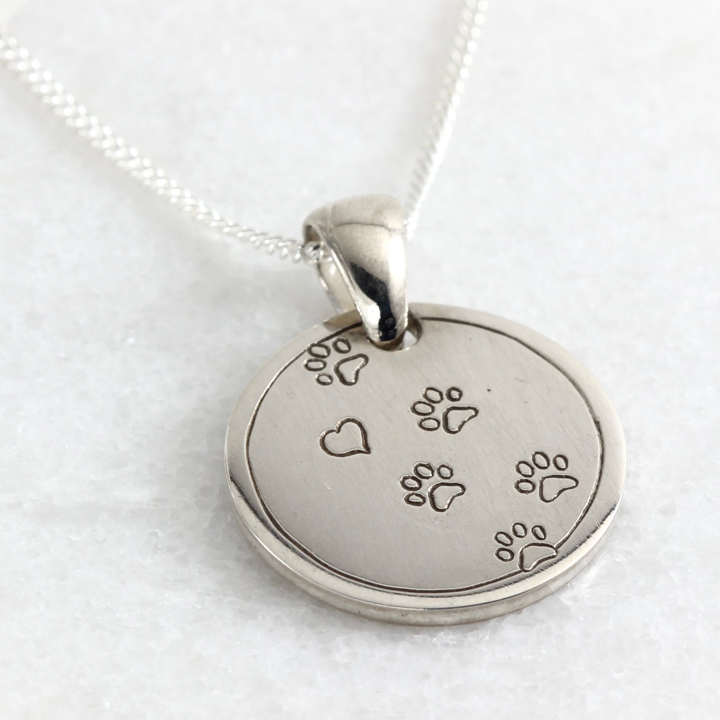 Small hand-engraved sterling silver pendant featuring paw prints and a heart