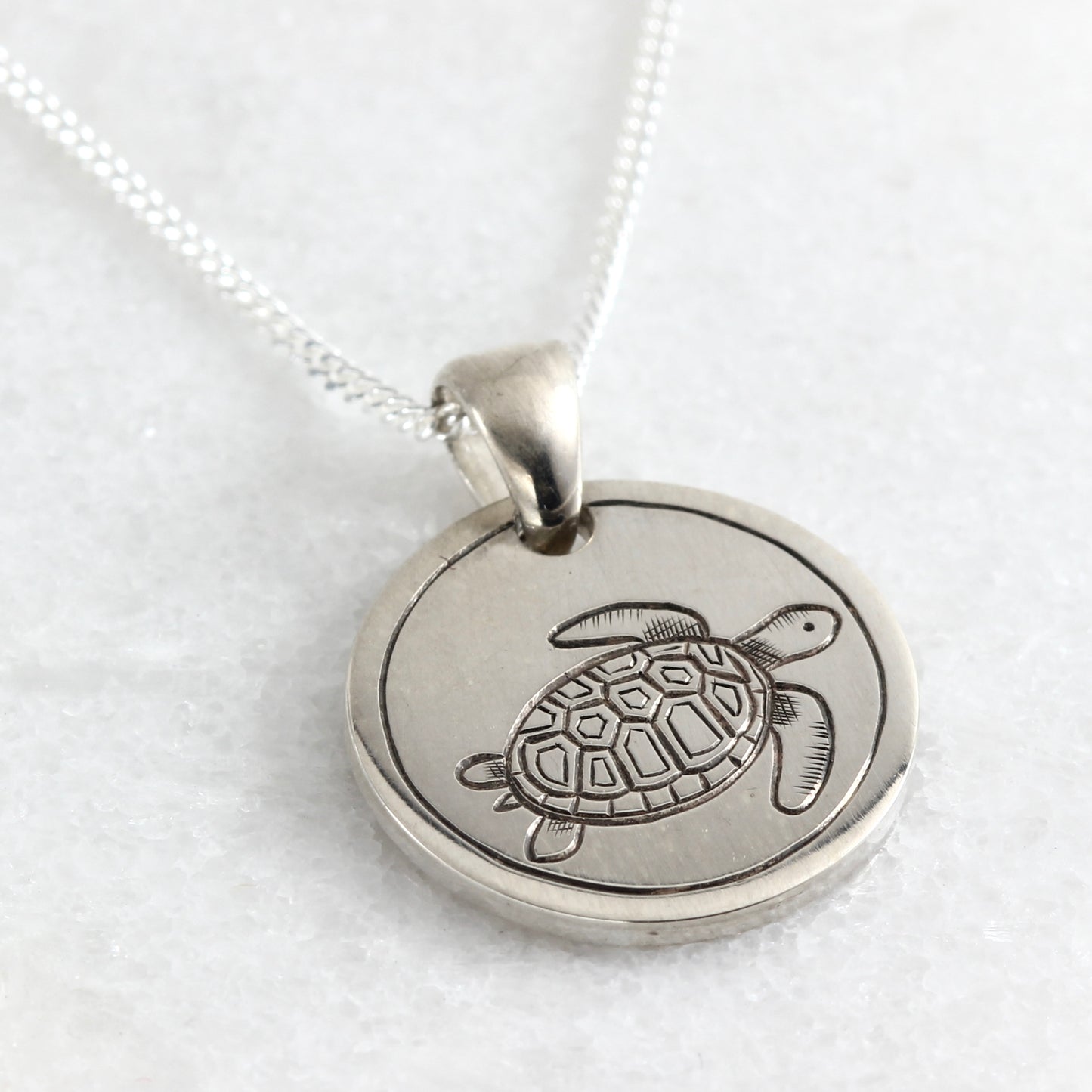 Small hand-engraved sterling silver pendant featuring a sea turtle.