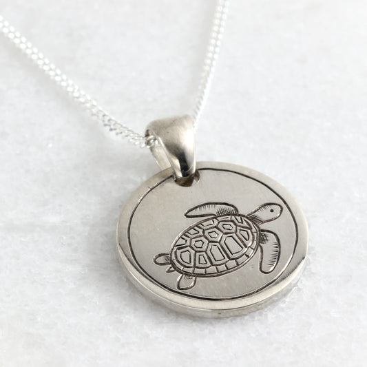 Small hand-engraved sterling silver pendant featuring a sea turtle.
