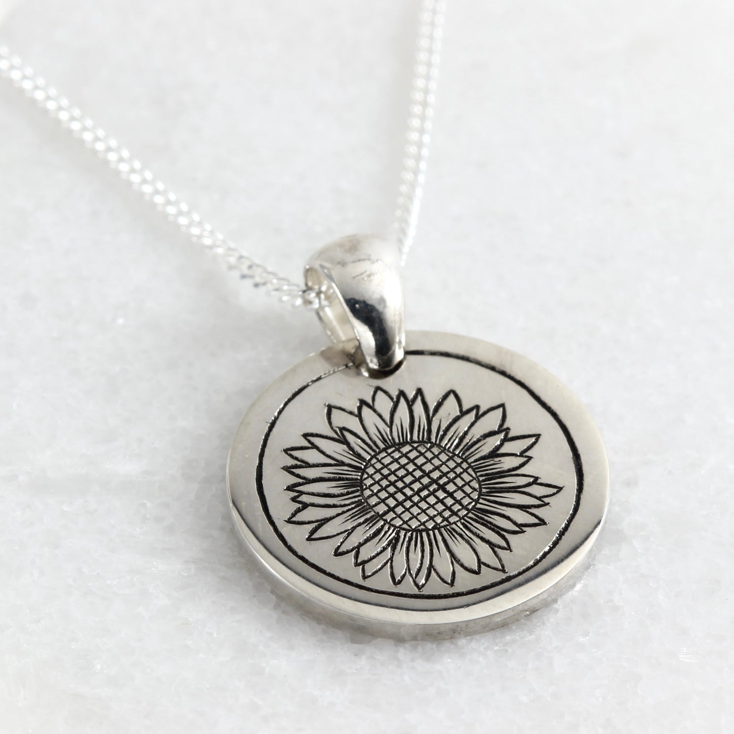 Small hand-engraved sterling silver pendant featuring a sunflower