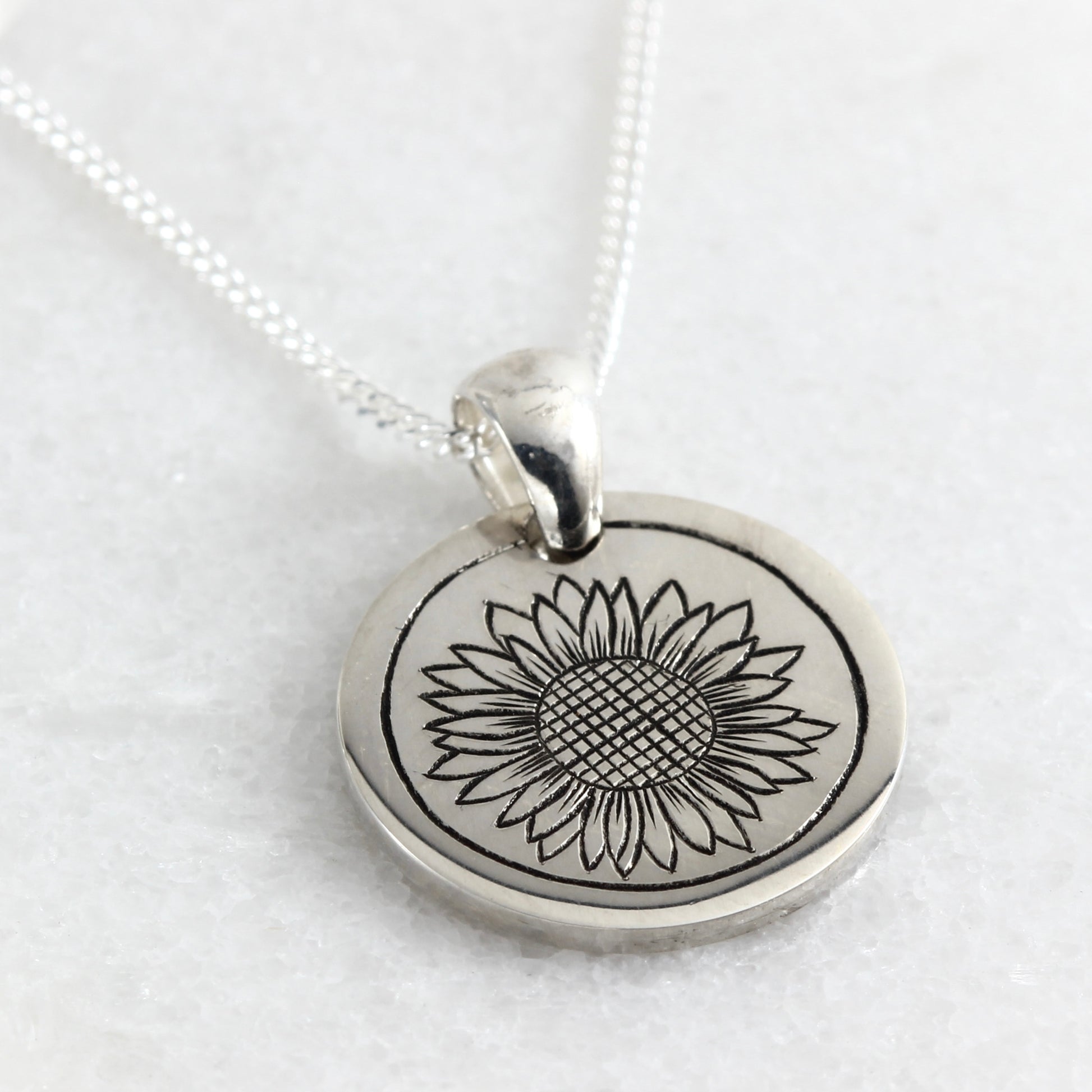 Small hand-engraved sterling silver pendant featuring a sunflower
