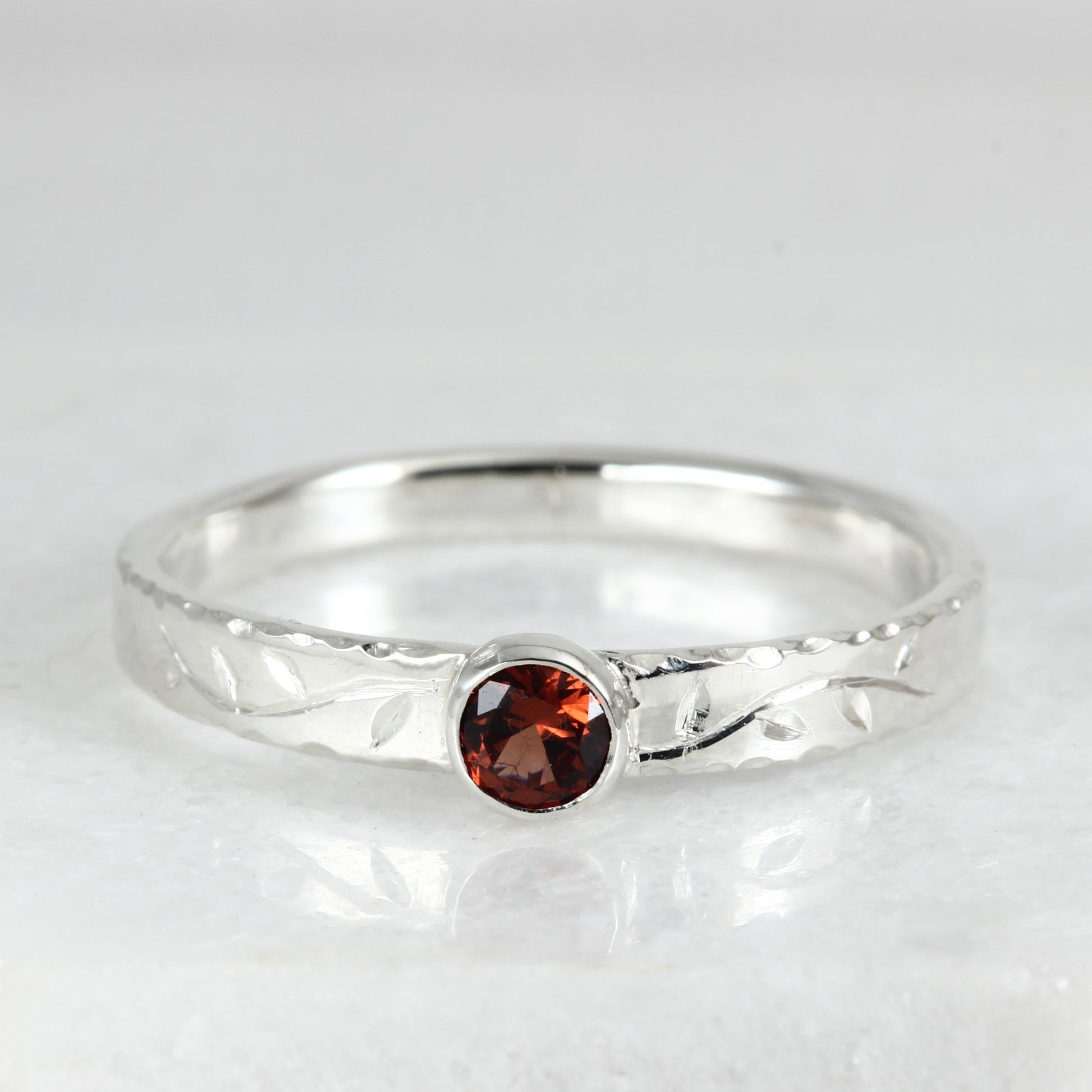 Front view of the Tendril Solitaire Ring in sterling silver, showing the gemstone and the hand engraved vine.