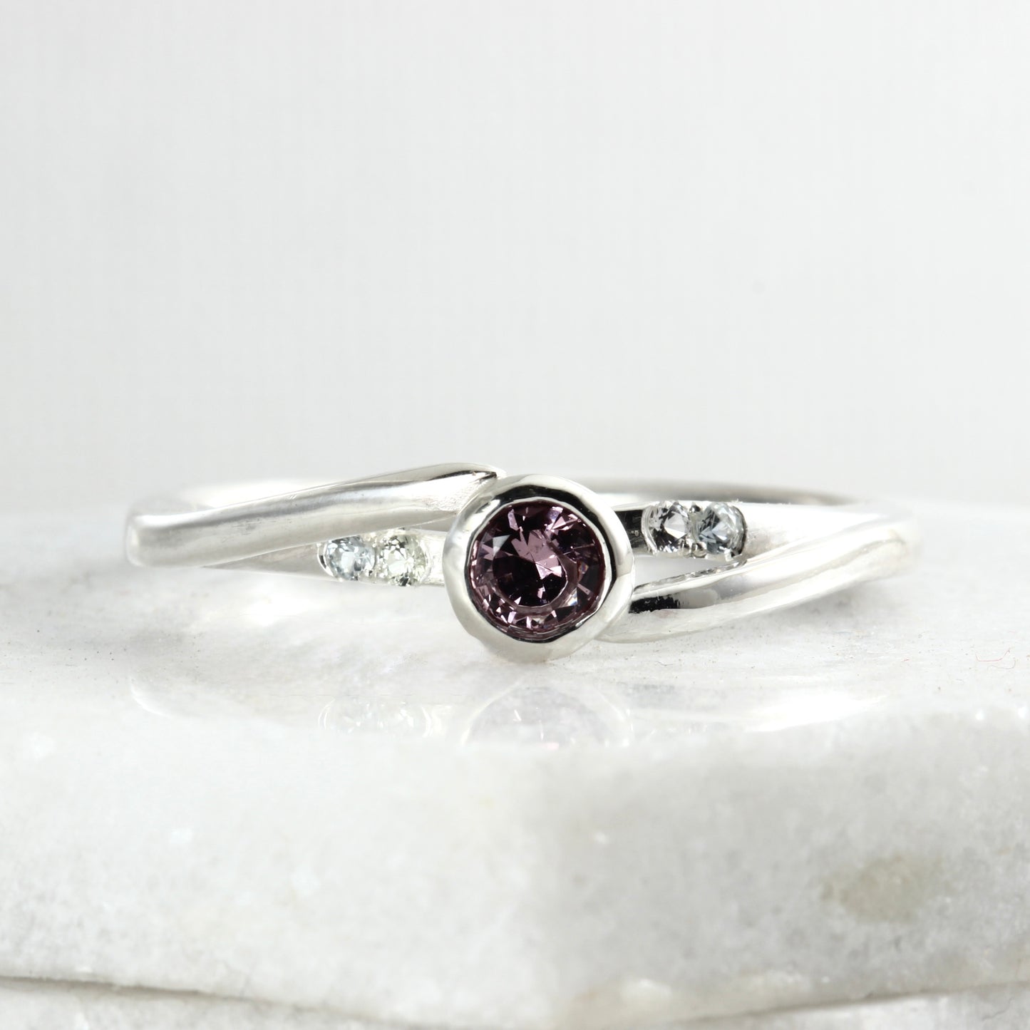 Front view of a sterling silver solitaire ring featuring a large garnet and four small Montana sapphires.