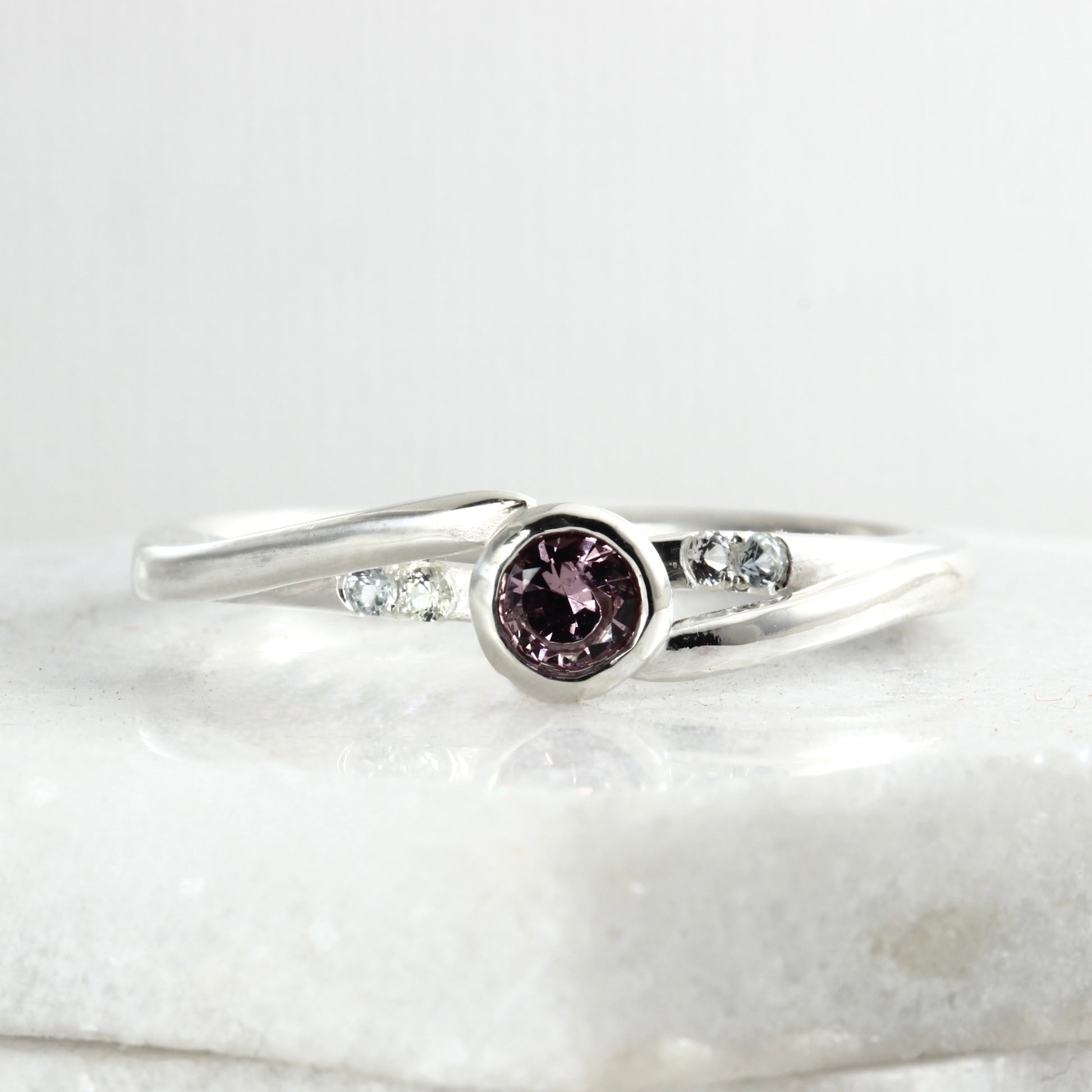 Front view of a sterling silver solitaire ring featuring a large garnet and four small Montana sapphires.