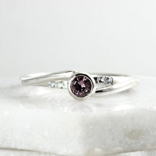 Front view of a sterling silver solitaire ring featuring a large garnet and four small Montana sapphires.