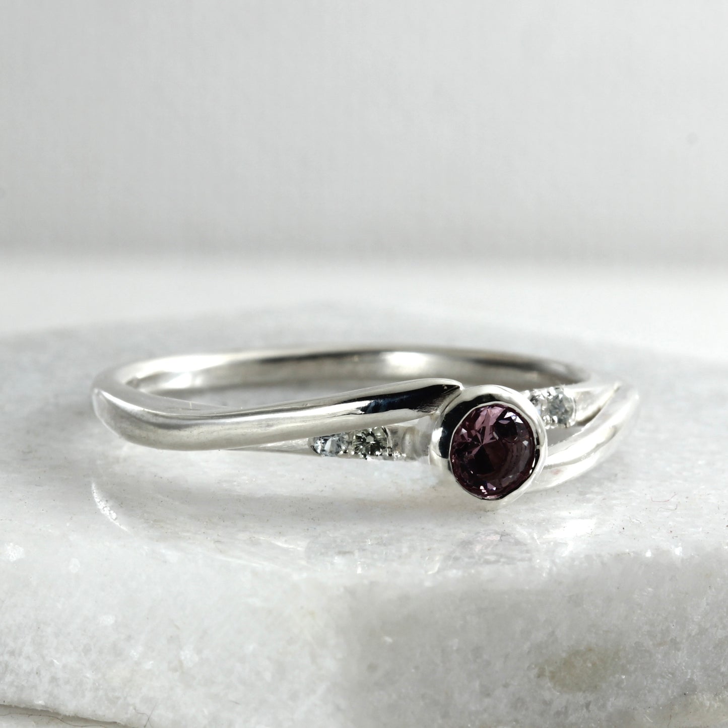 Side view of a sterling silver solitaire ring featuring a large garnet and four small Montana sapphires.