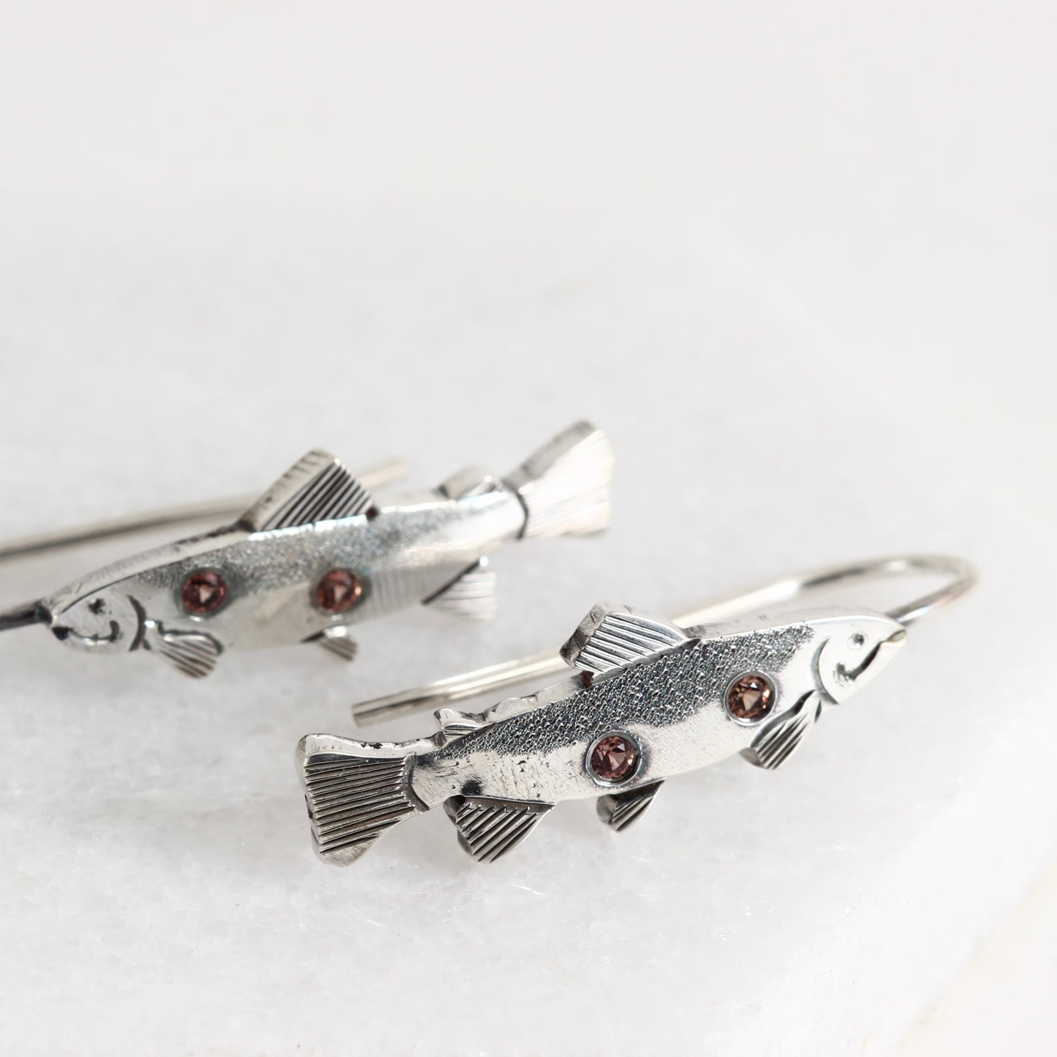 Hand-fabricated and engraved sterling silver fish dangle earrings with Padparadscha sapphires.
