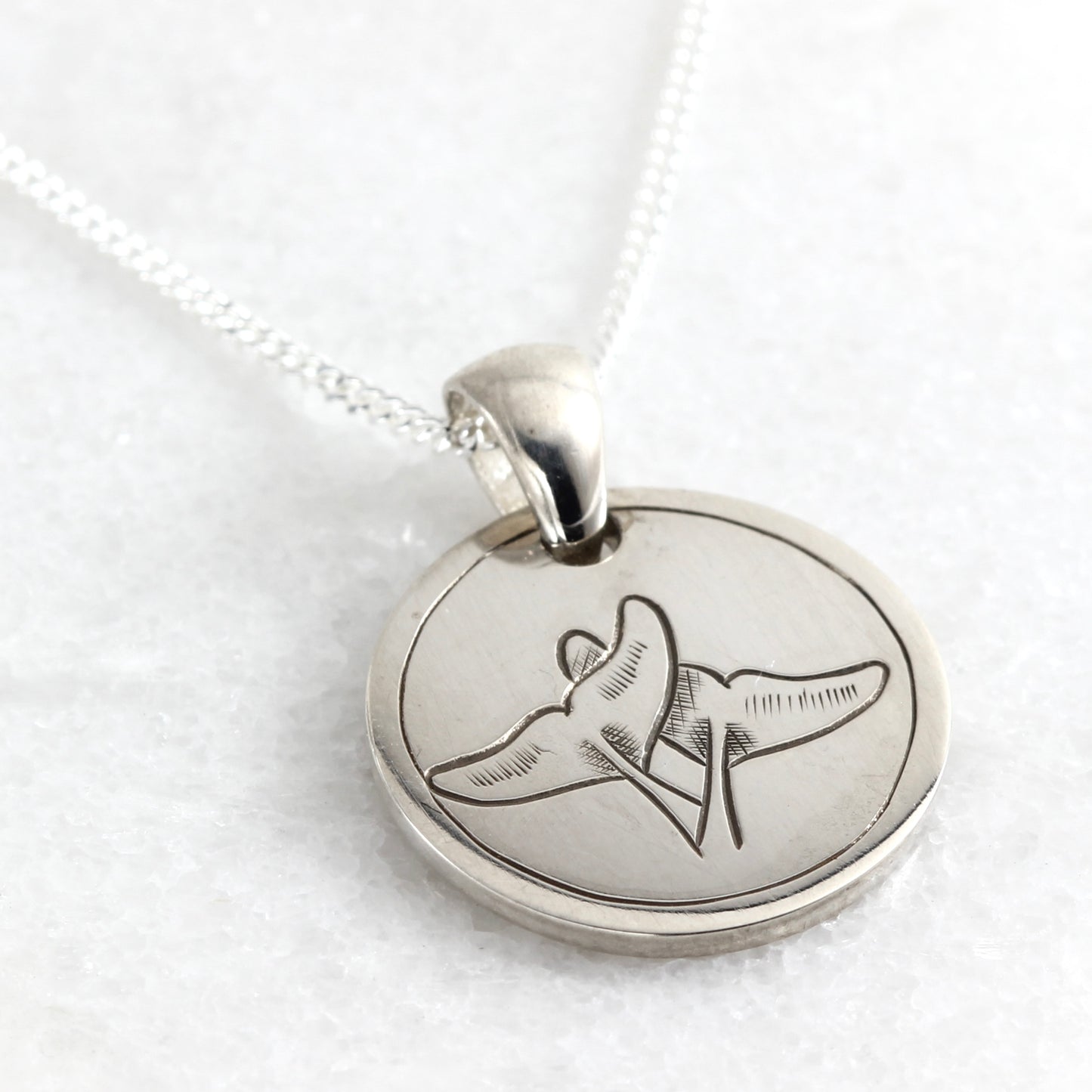Small hand-engraved sterling silver pendant featuring whale tails