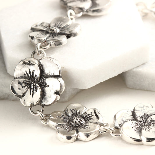 Hand-formed sterling silver bracelet featuring linked floral elements, shaped using chasing and repoussé. A sculptural, articulated piece inspired by natural bloom.