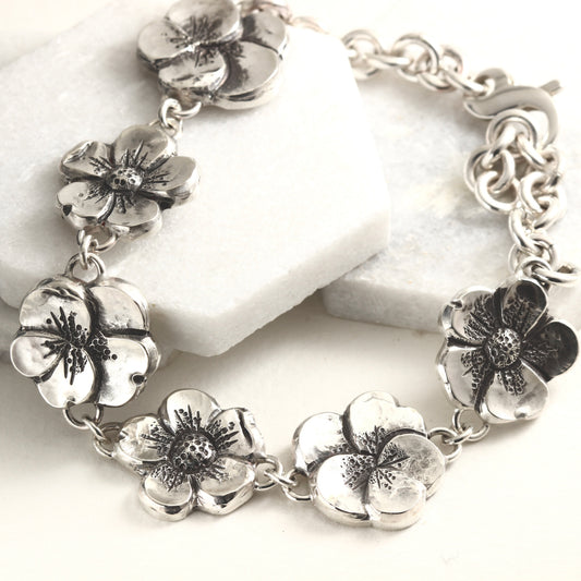 Hand-formed sterling silver bracelet featuring linked floral elements, shaped using chasing and repoussé. A sculptural, articulated piece inspired by natural bloom.