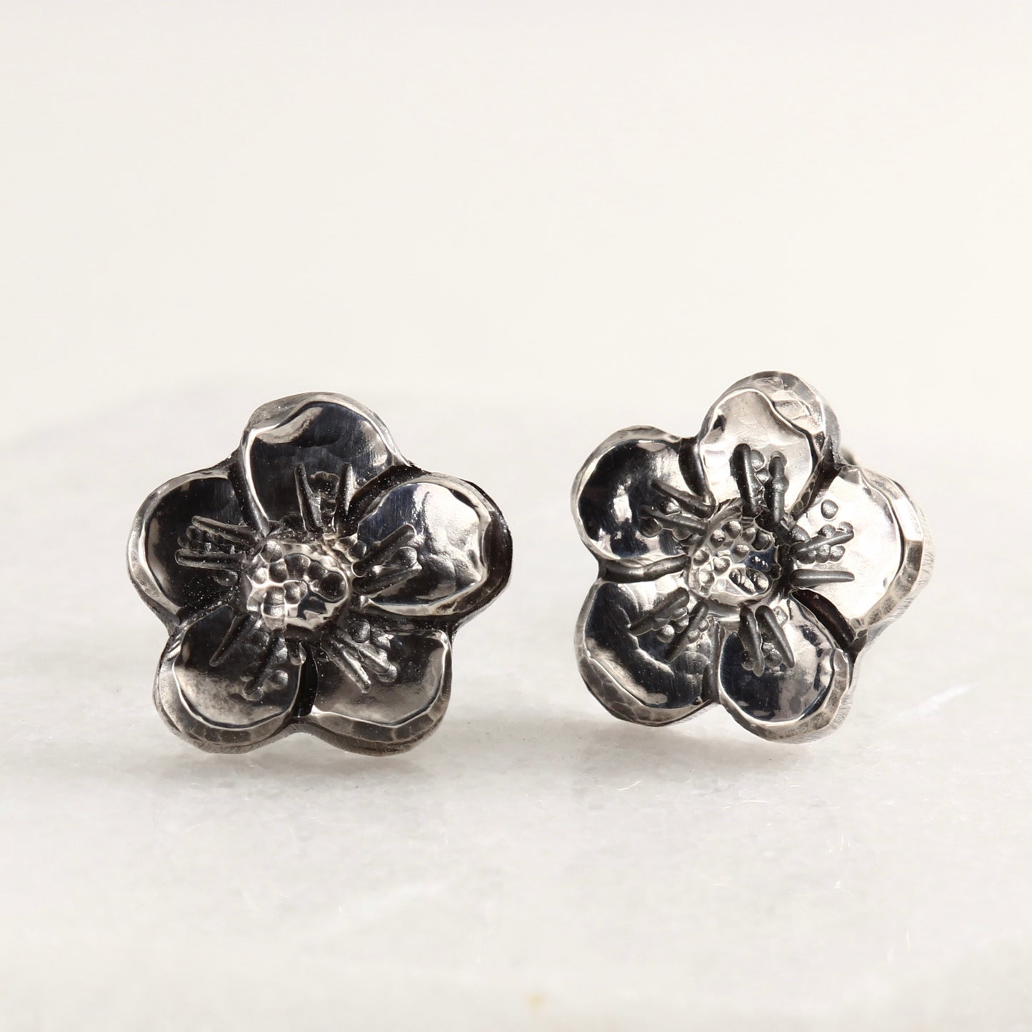 Wild Bloom Stud Earrings in sterling silver, handcrafted floral studs, on marble background