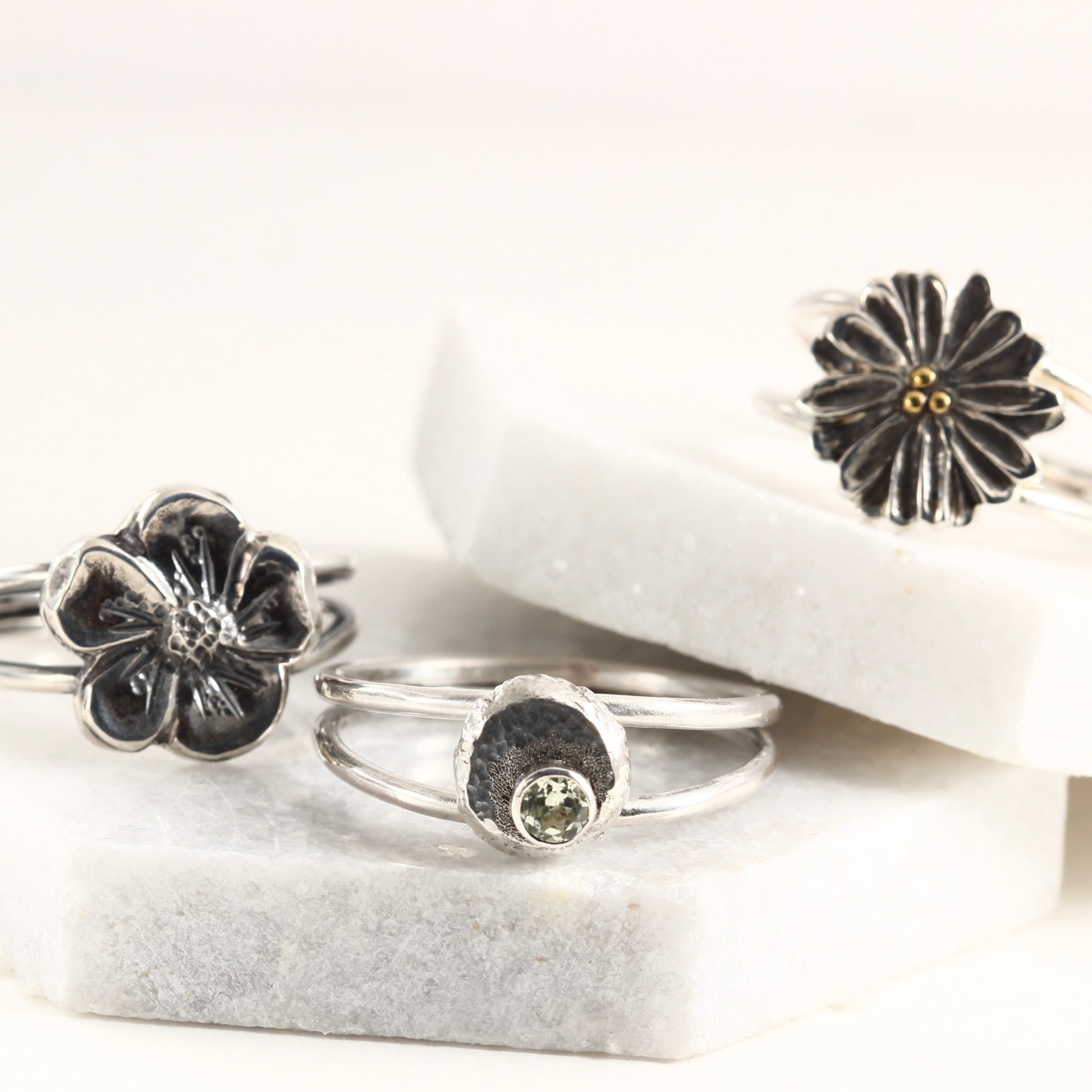 A group of rings from the Wild Blooms collection, sterling silver and hand formed shown on white marble tile