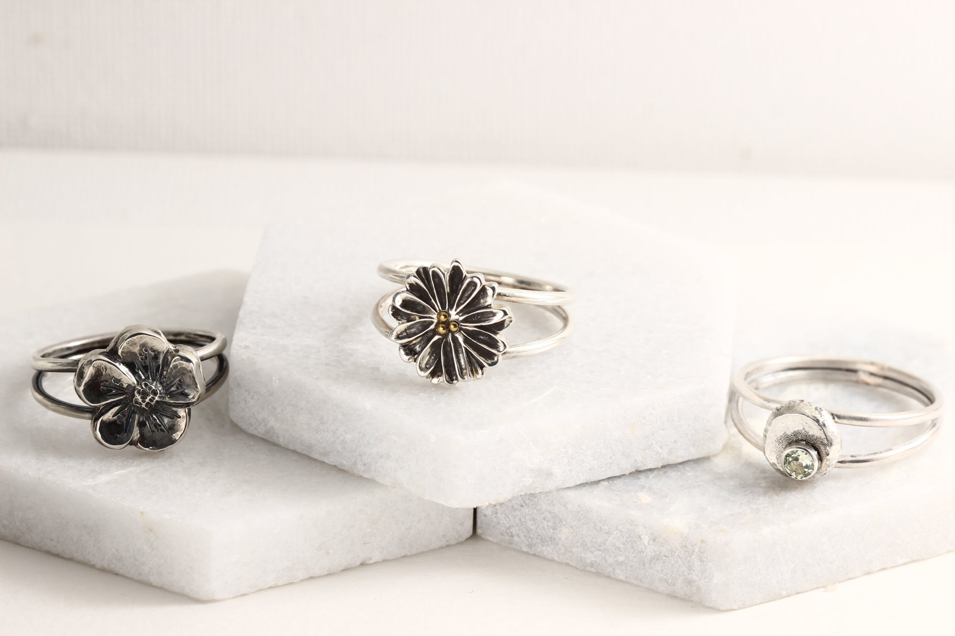 Several rings from the Wild Blooms collection in sterling silver, handcrafted flower rings, on a white marble background