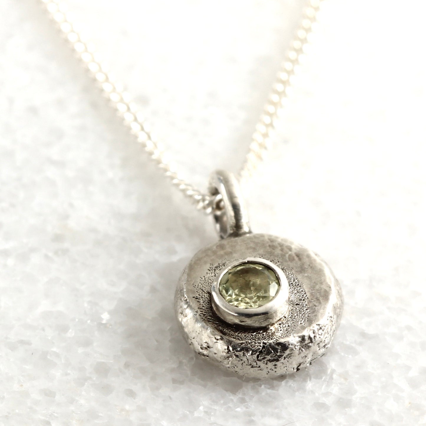 Wild Bud Pendant in sterling silver with Montana Sapphire, shown on white marble