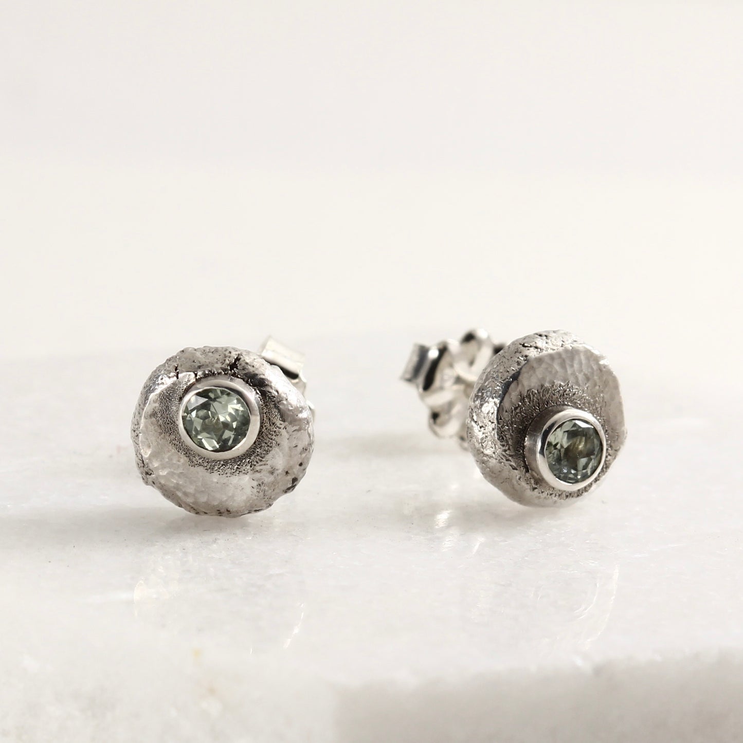 Wild Bud Stud Earrings in sterling silver with Montana sapphires, shown on a white marble tile