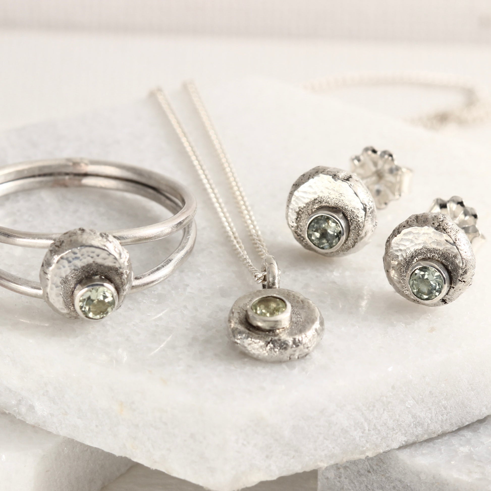 A group of jewelry from the Wild Buds series, sterling silver with Montana sapphires, shown on white marble tile