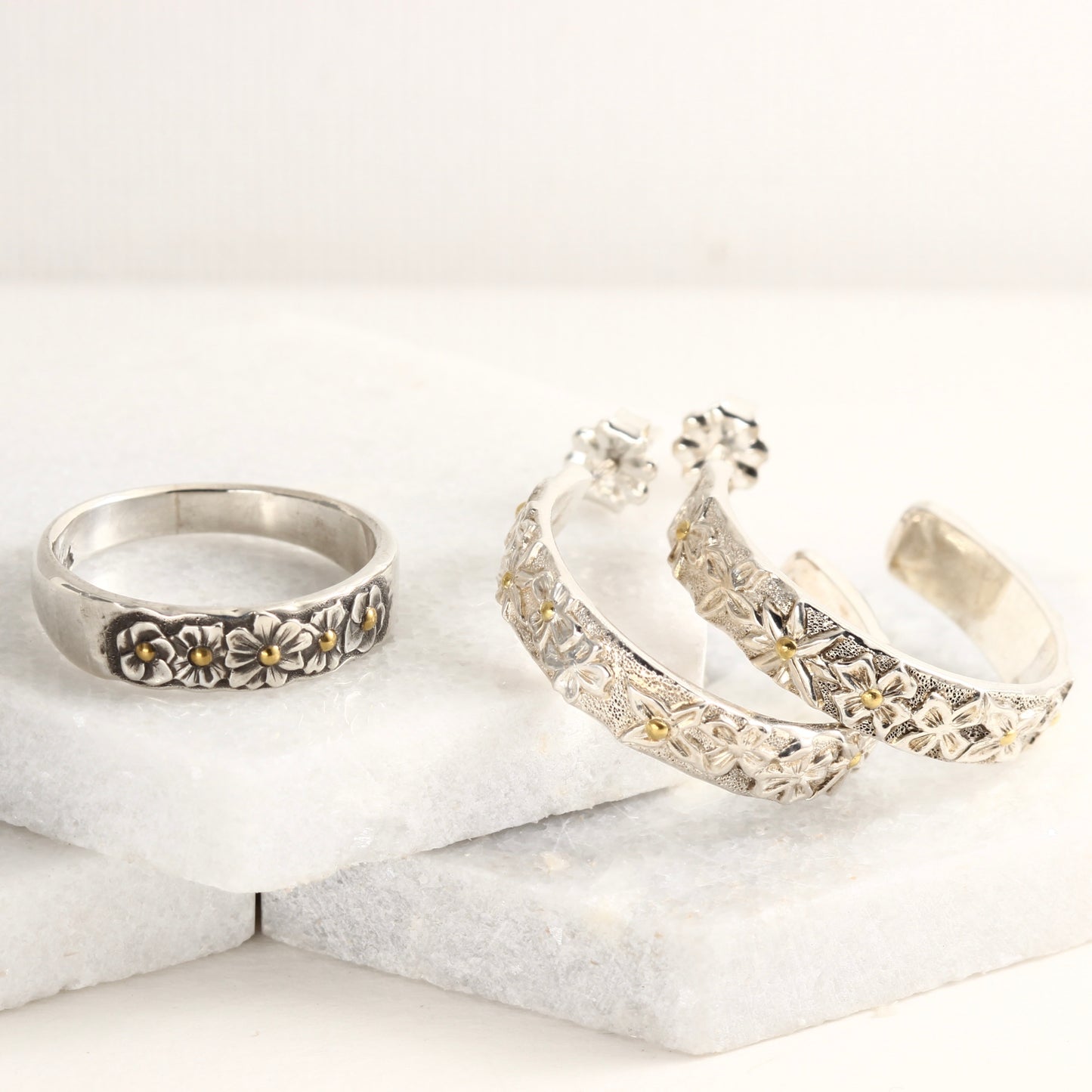 Wild Meadow Half Band and Hoop Earrings, hand carved flower jewelry shown on a white marble tile