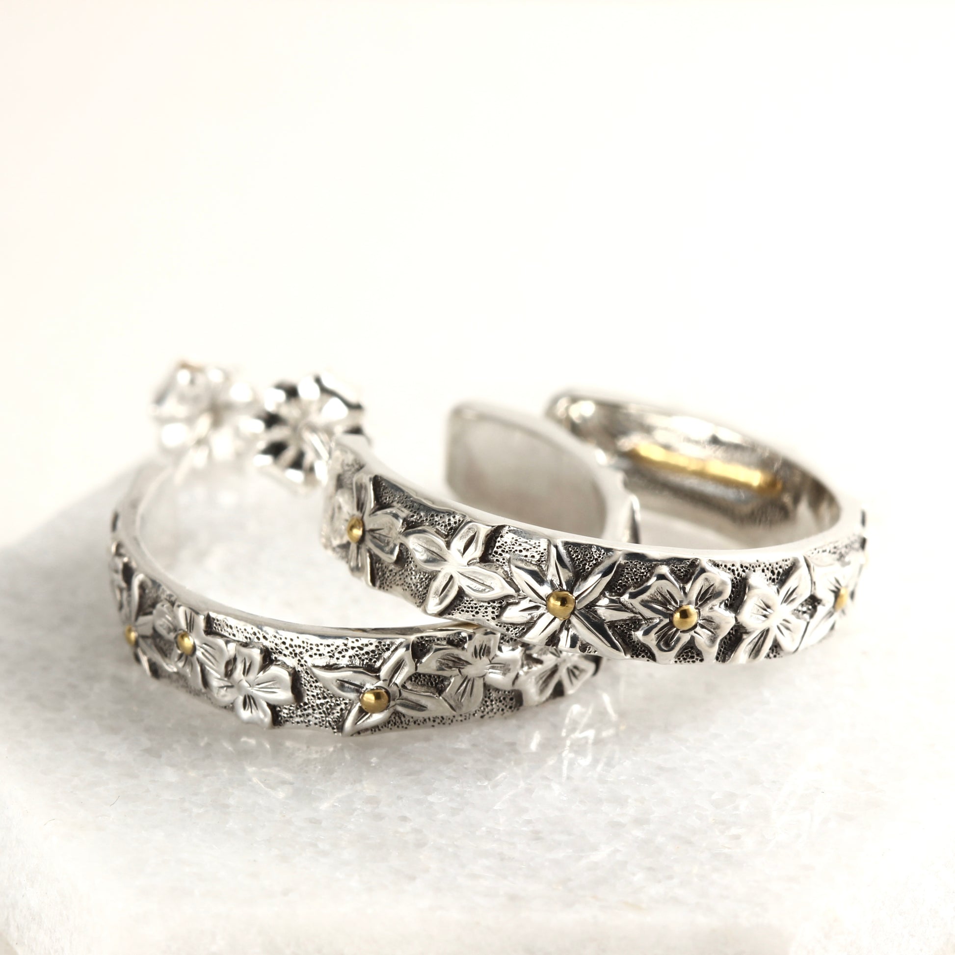 Wild Meadow Hoop Earrings in sterling silver with gold accents, hand carved earrings on a white marble background