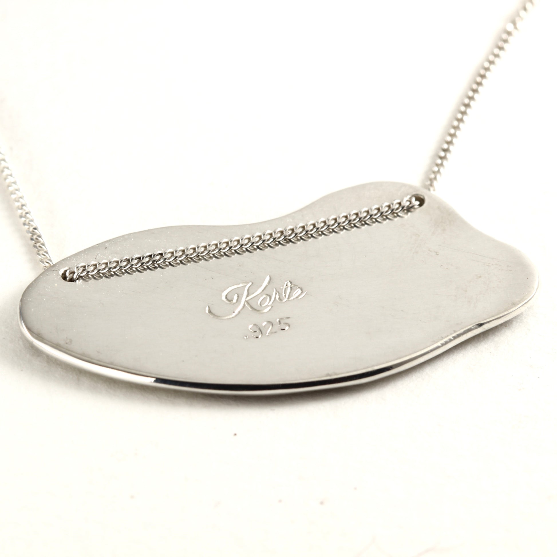 Back Side of Wild Meadow Spring Branch Pendant in sterling silver with gold accents, a hand carved flower pendant shown on white marble tile