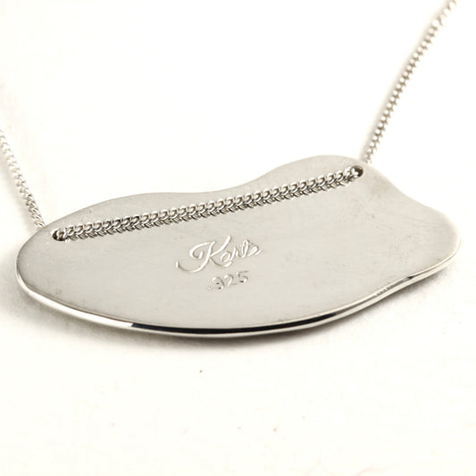 Back Side of Wild Meadow Spring Branch Pendant in sterling silver with gold accents, a hand carved flower pendant shown on white marble tile