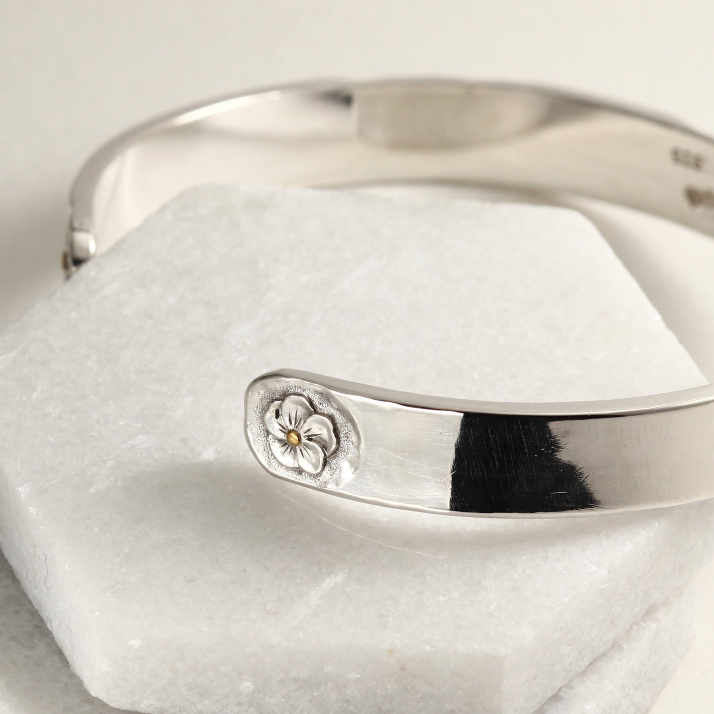 Close up of hand-formed sterling silver cuff with 24k gold accents and engraved texture