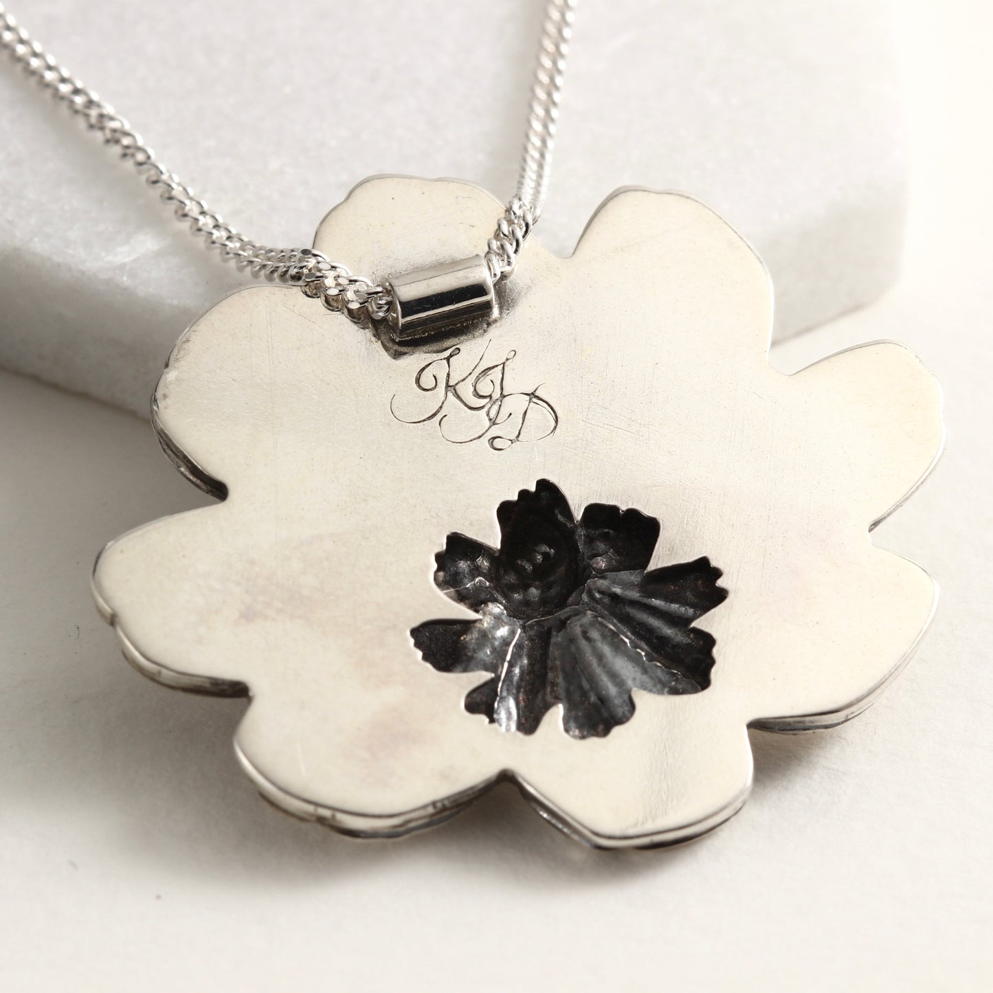 Back view of Wild Radiance Cosmos Pendant, a handcrafted flower necklace, showing cut out detail