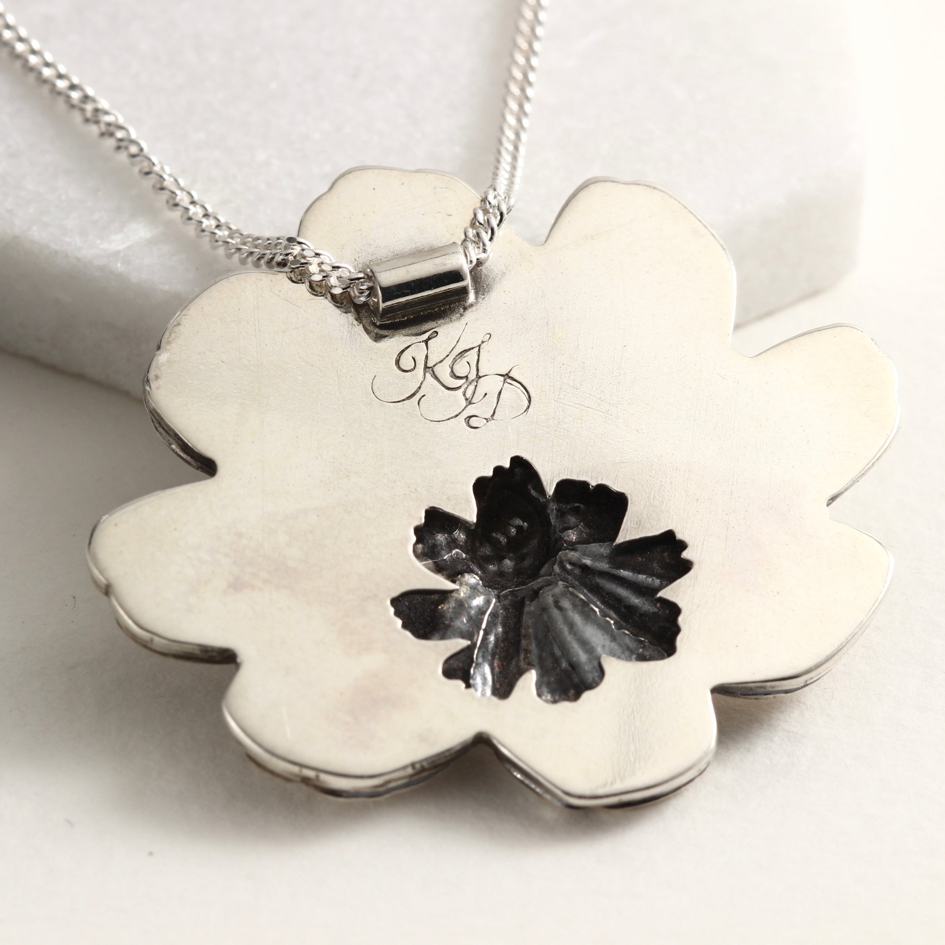 Back view of Wild Radiance Cosmos Pendant, a handcrafted flower necklace, showing cut out detail