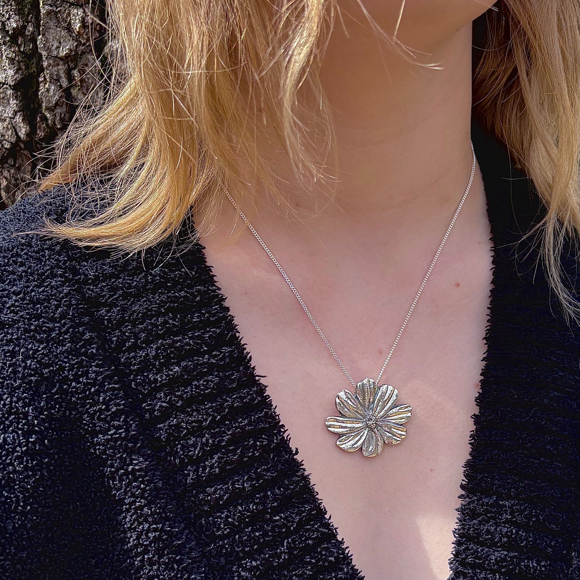 Wild Radiance Cosmos Pendant in sterling silver, a handcrafted flower necklace shown on a model
