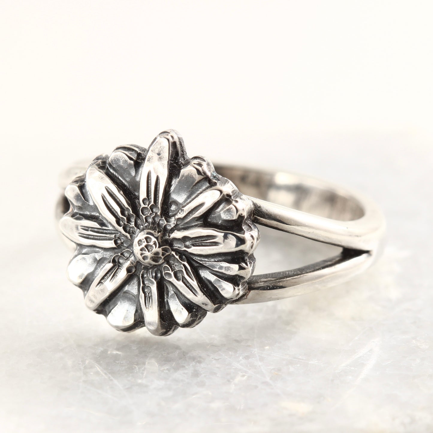 Wild Radiance Ring in sterling silver, handcrafted flower ring on a white marble tile