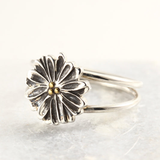 Wild Radiance Ring with gold center in sterling silver, a handcrafted flower ring, on a white marble tile