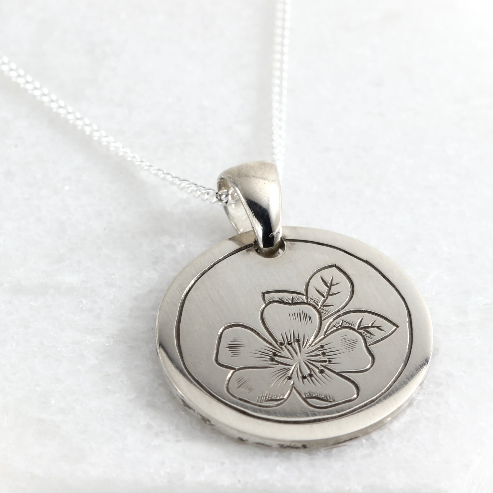 Small hand-engraved sterling silver pendant featuring a wild rose